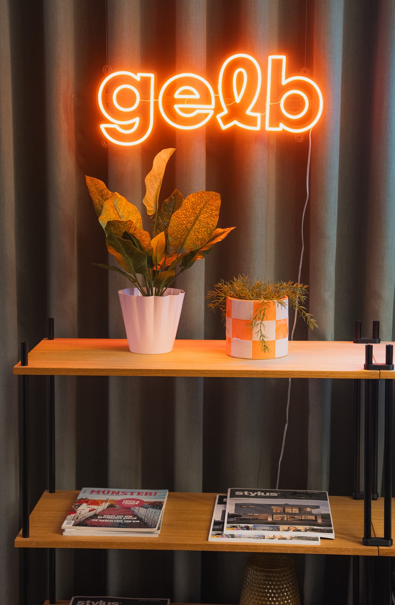 Neon-Logo gelb über einem KUUDU Boden mit Pflanzen